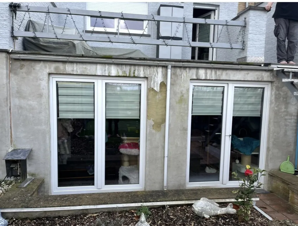 La façade arrière avant travaux : enduit gris et taché autour des portes-fenêtres, sous la terrasse