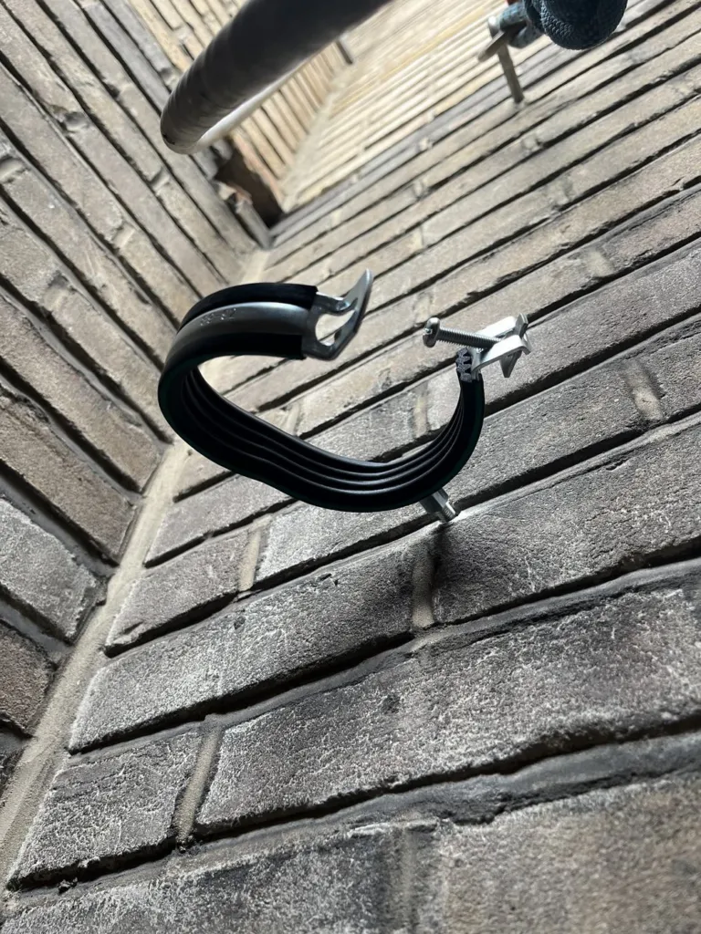 Un collier de fixation noir vissé dans le mur de brique du puits, encore vide