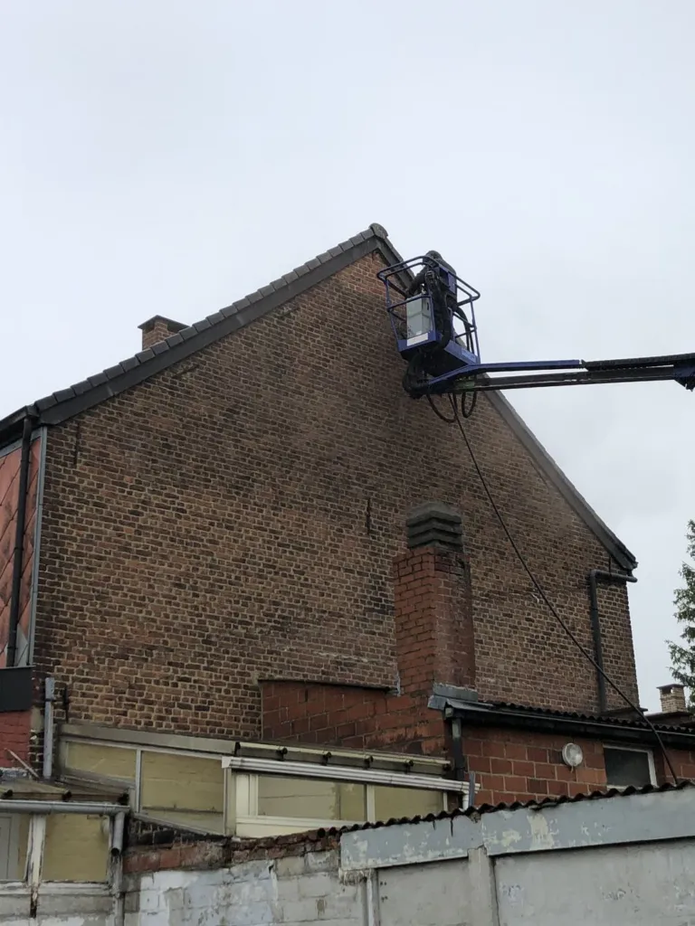 L'opérateur au travail en haut du pignon en briques, près de la rive de toiture