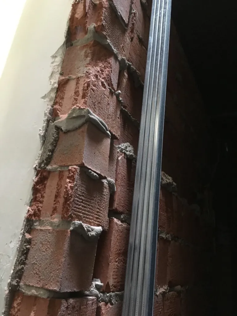 Un profilé métallique fixé sur la maçonnerie en brique de la gaine, pendant les travaux