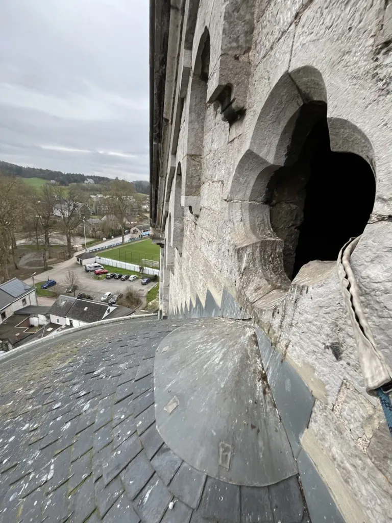 La couverture en ardoise au pied du clocher et l'ouverture découpée dans la tour