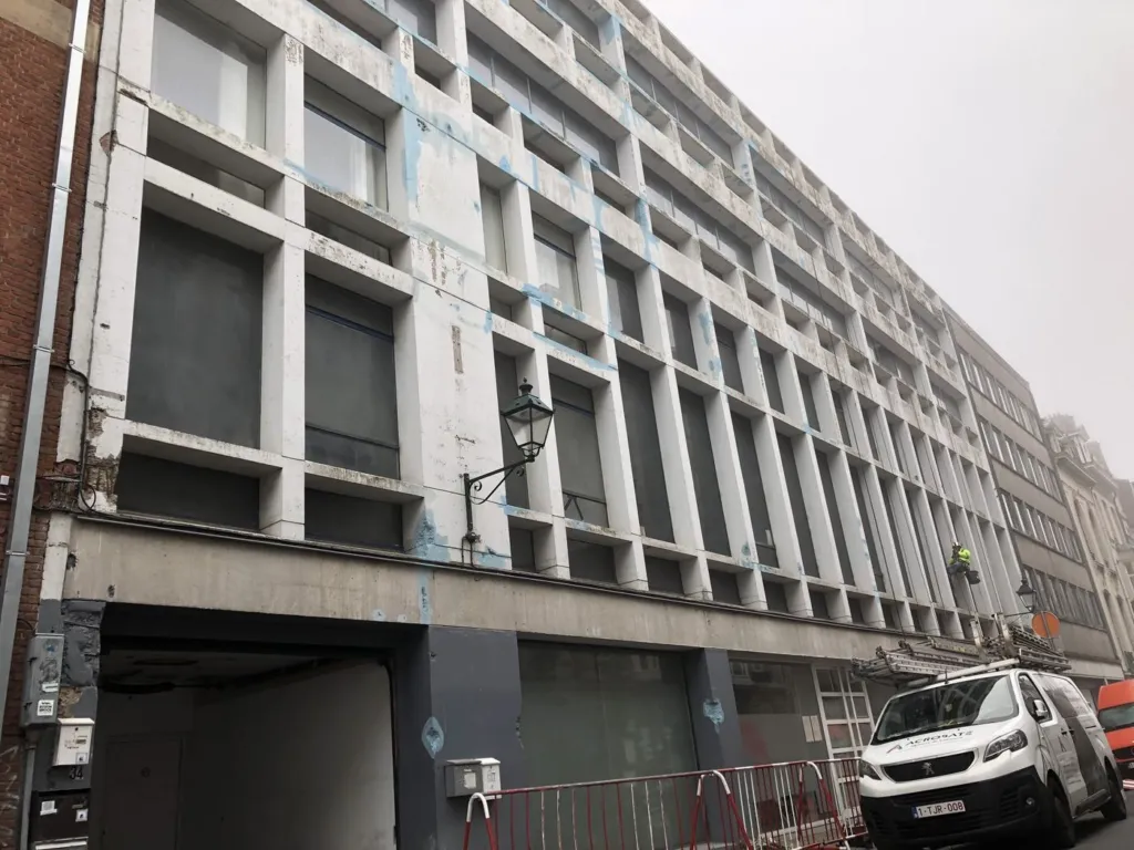 L'immeuble de bureaux à trame de béton blanc, vu depuis la rue, barrières au pied