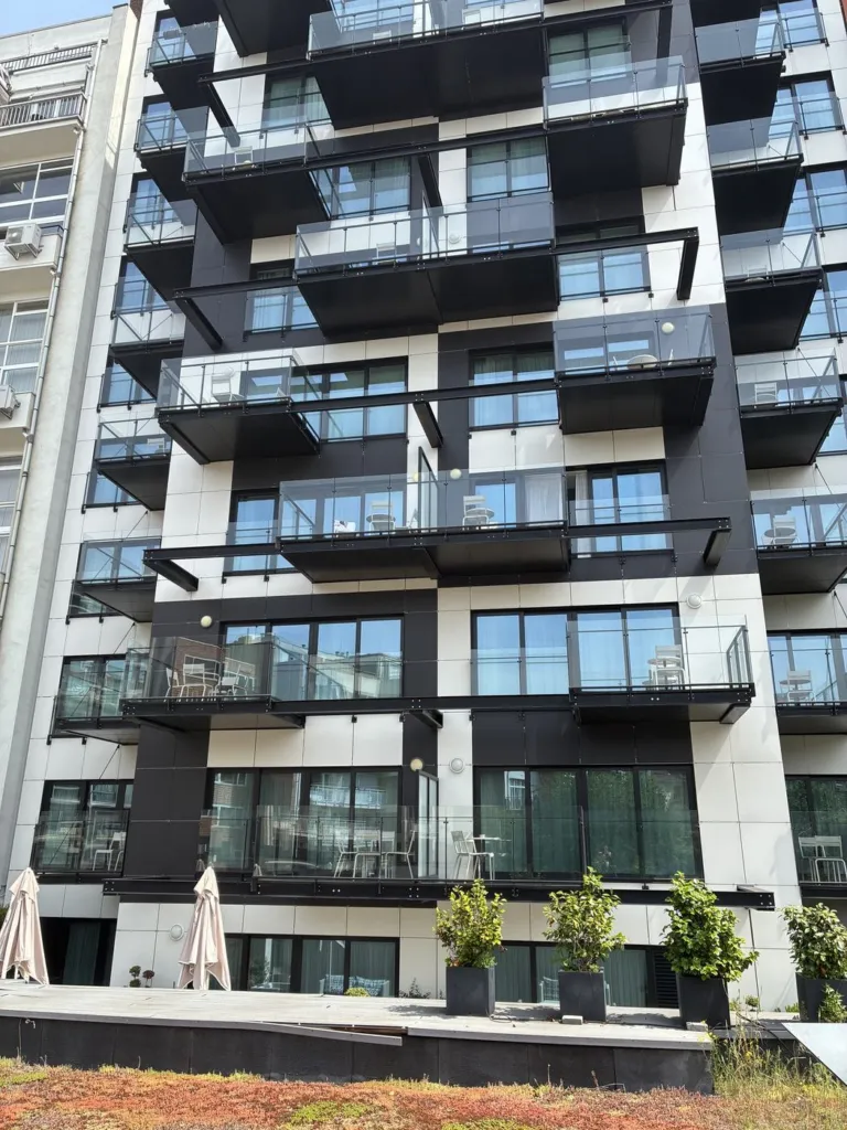 L'immeuble et ses balcons portés par des poutres métalliques noires, vus du sol