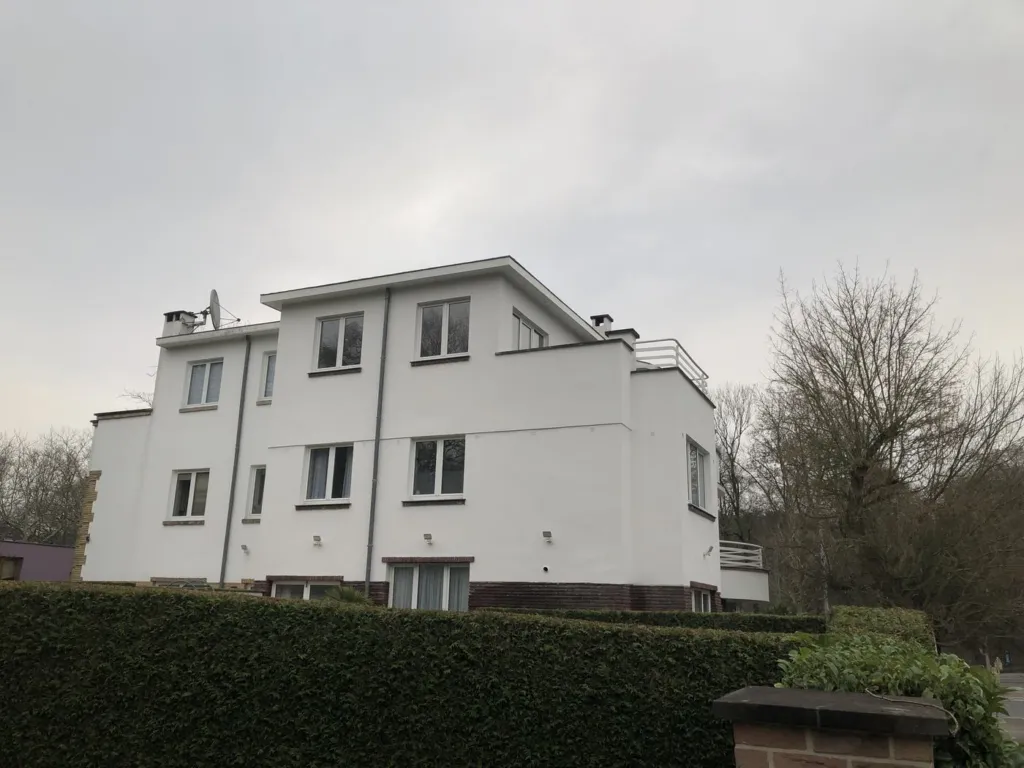 Le bâtiment aux balcons arrondis après rénovation, façades blanches, vu depuis la rue