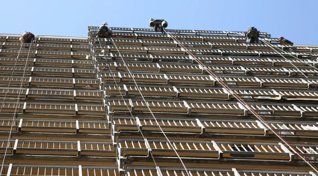 La tour de logements vue depuis le sol, rangées de balcons continus et cordes tendues sur la façade