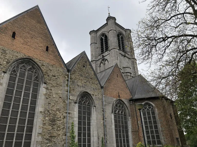 Une église en pierre et sa tour à horloge, vue de côté