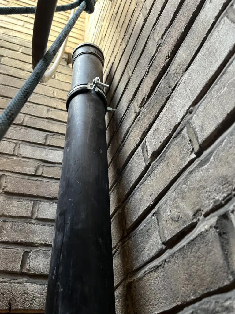 La canalisation noire installée dans le collier contre la maçonnerie, la corde à côté
