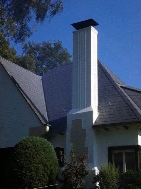 La cheminée d'une villa après rénovation de son revêtement, finition blanche sur le toit d'ardoise