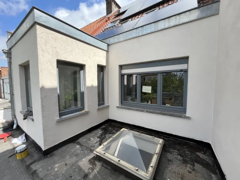 L'annexe d'une maison après ravalement, enduit clair, lanterneau sur la toiture plate