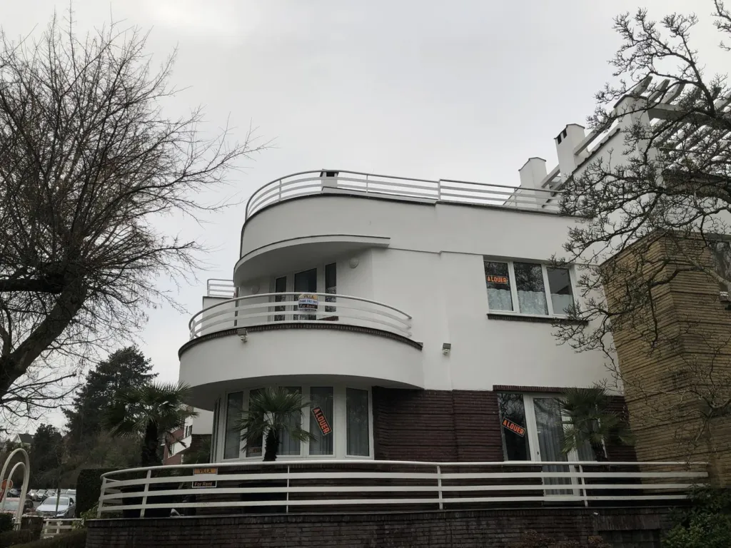 Après : le même bâtiment, façades blanches et lisses, balcons repris, sans échafaudage
