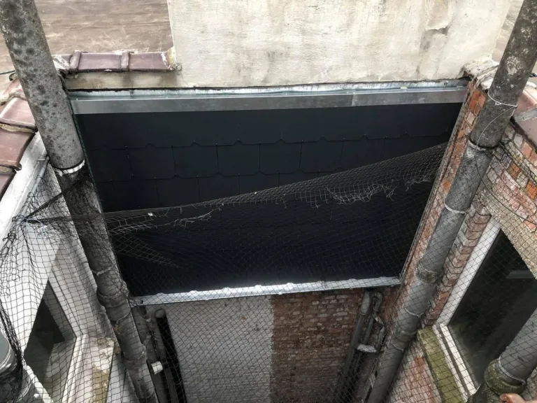La paroi d'une courette bruxelloise habillée d'ardoises, vue depuis la toiture
