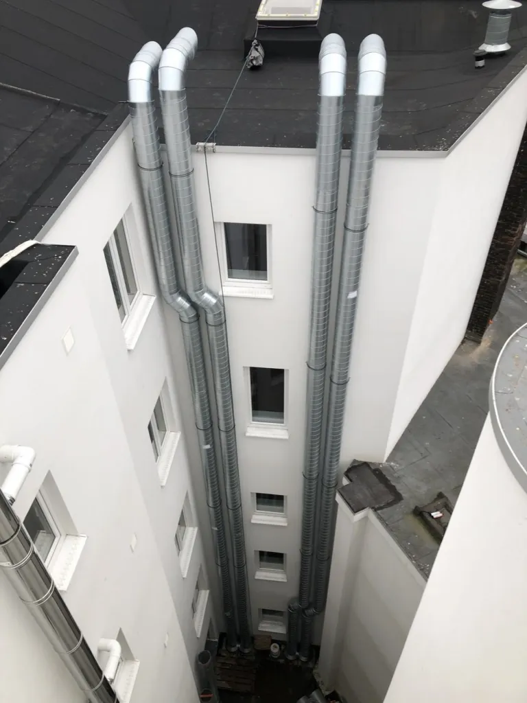 Quatre conduits d'aération montant jusqu'à la toiture dans une cour intérieure à Liège