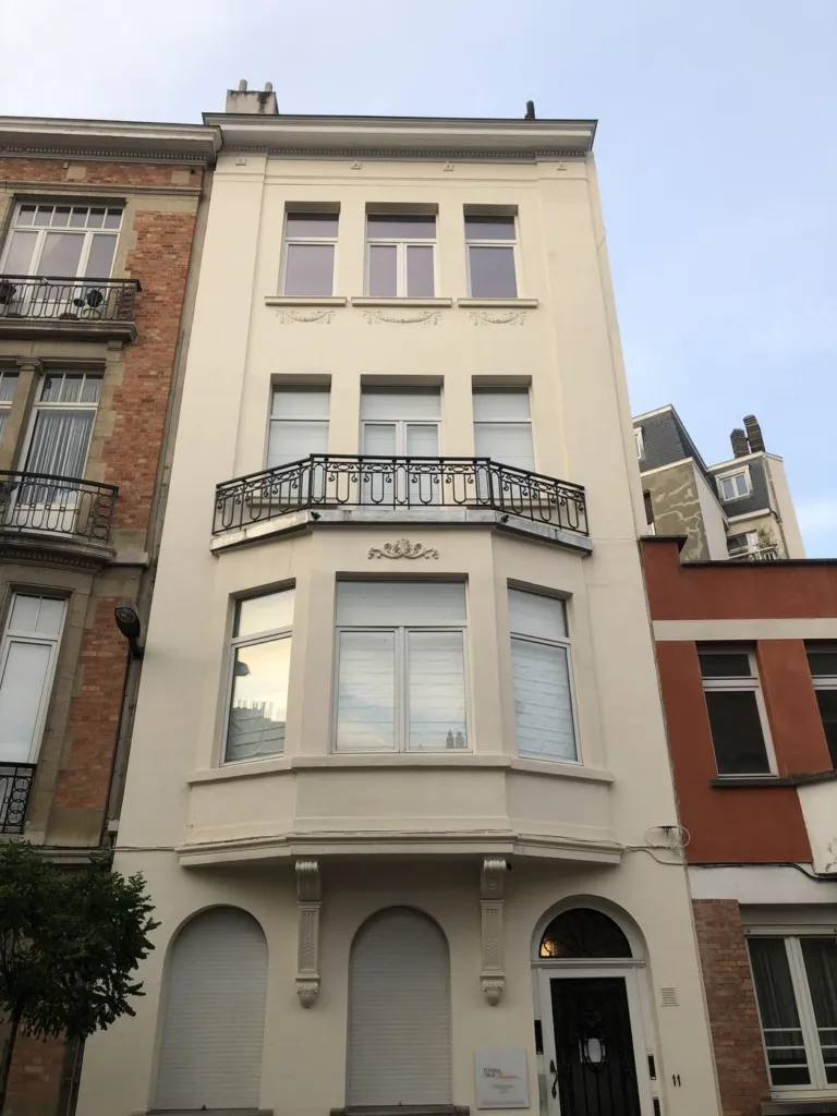 Une maison de ville à bow-window et balcon en fer forgé, façade restaurée en finition claire