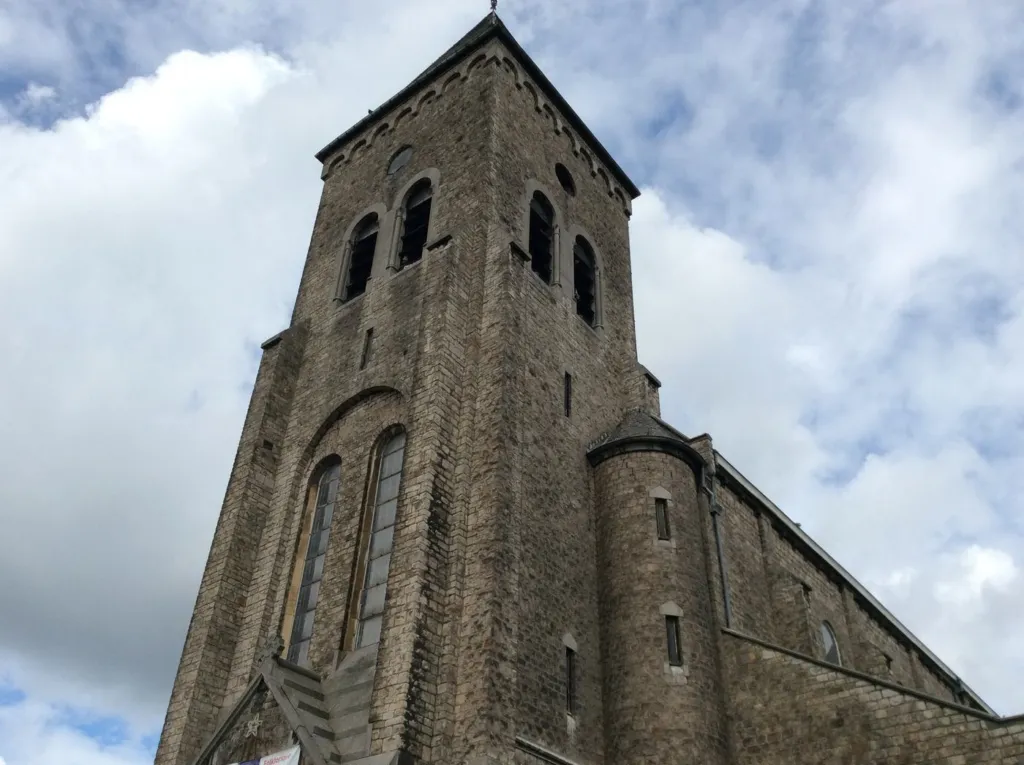 Le clocher en pierre et la façade de l'église en contre-plongée