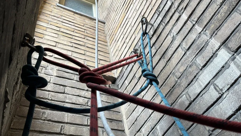 Les cordes amarrées et nouées dans le volume étroit entre les deux murs de brique
