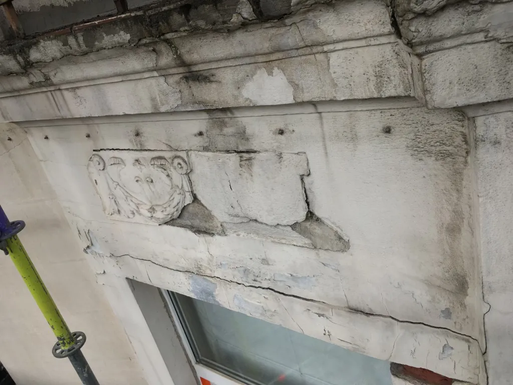 L'état initial d'un décor mouluré et de l'enduit fissuré sous une fenêtre