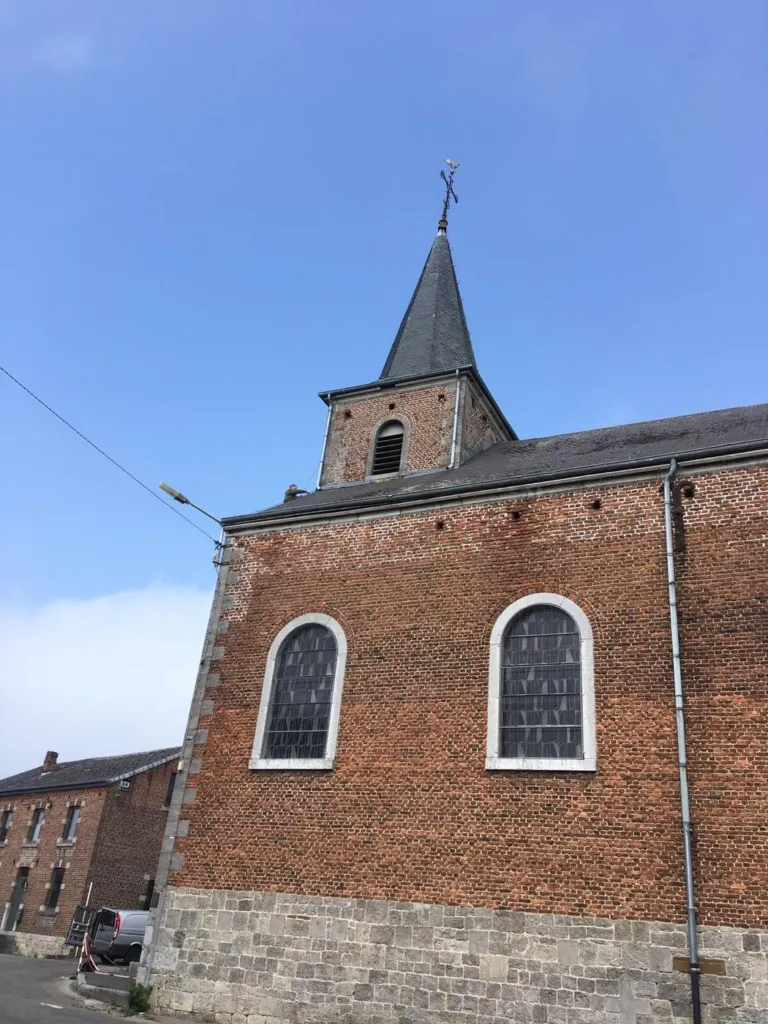 La façade latérale en brique de l'église et son clocher, ciel bleu