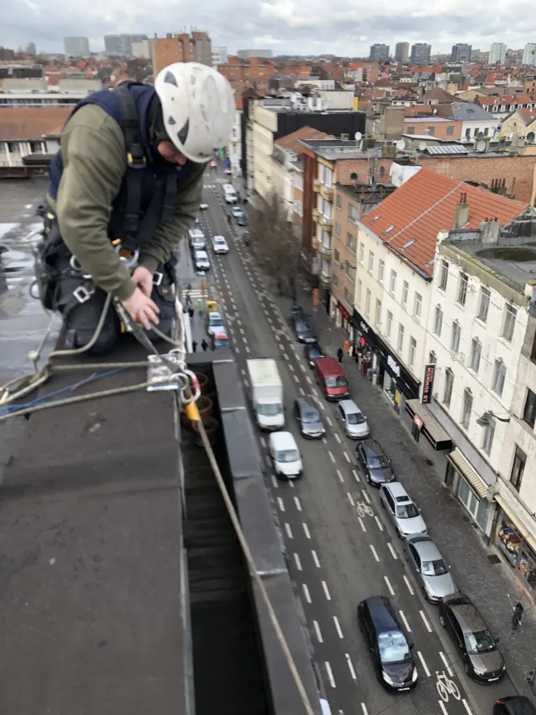 Un cordiste s'engage depuis la toiture, la rue en contrebas