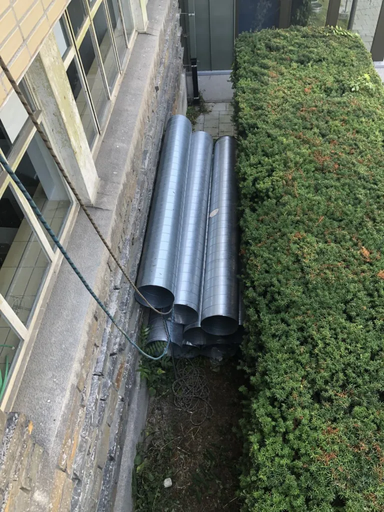Sections de conduits métalliques stockées au pied du bâtiment avant assemblage