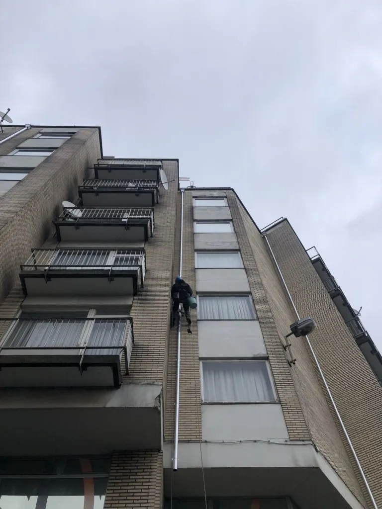Cordiste posant une descente en partie haute de la façade