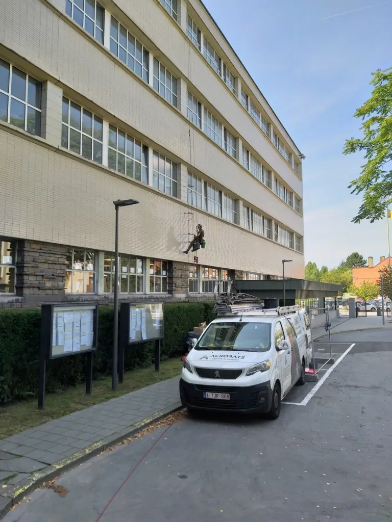 Cordiste en intervention le long de la façade à plusieurs niveaux, vue d'ensemble
