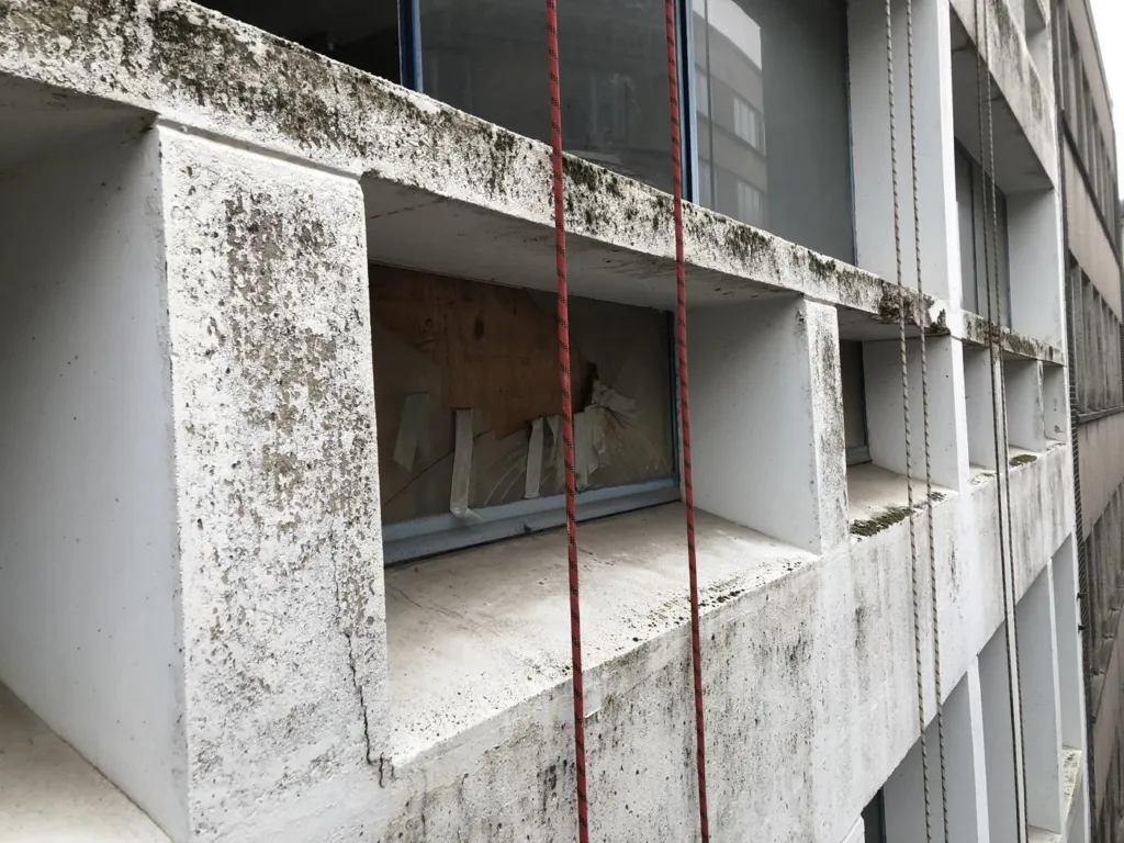 L'état des montants et traverses de béton autour d'une fenêtre, traces noires