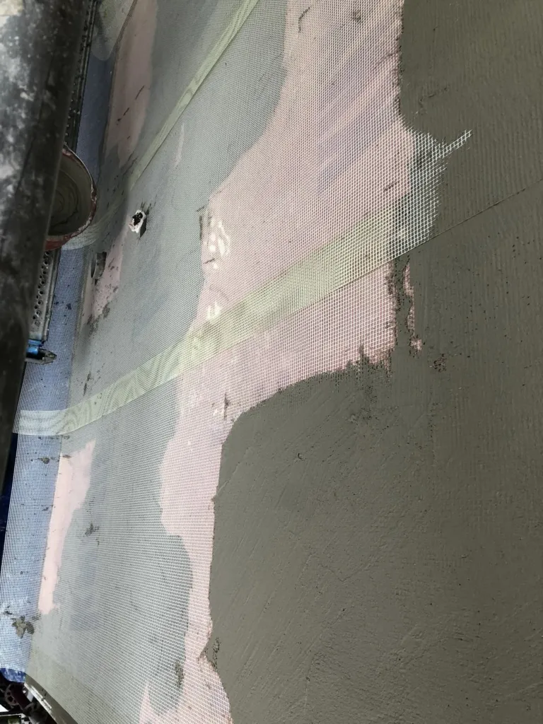 Un enduit de façade repris sur trame, entre la surface préparée et la finition