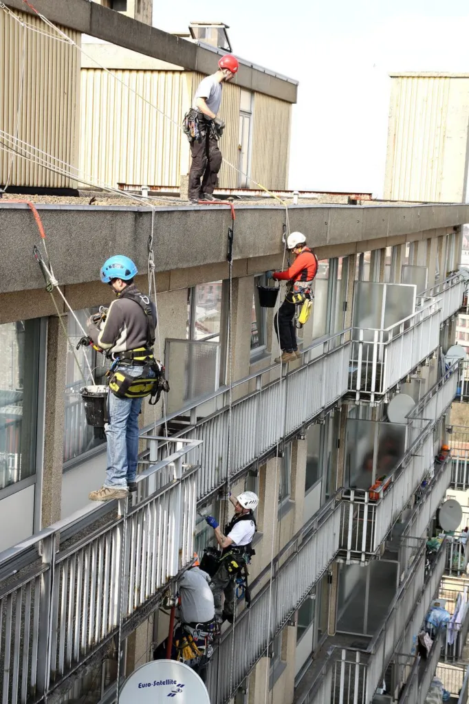 Vue verticale de la façade avec des cordistes à différents niveaux de balcons