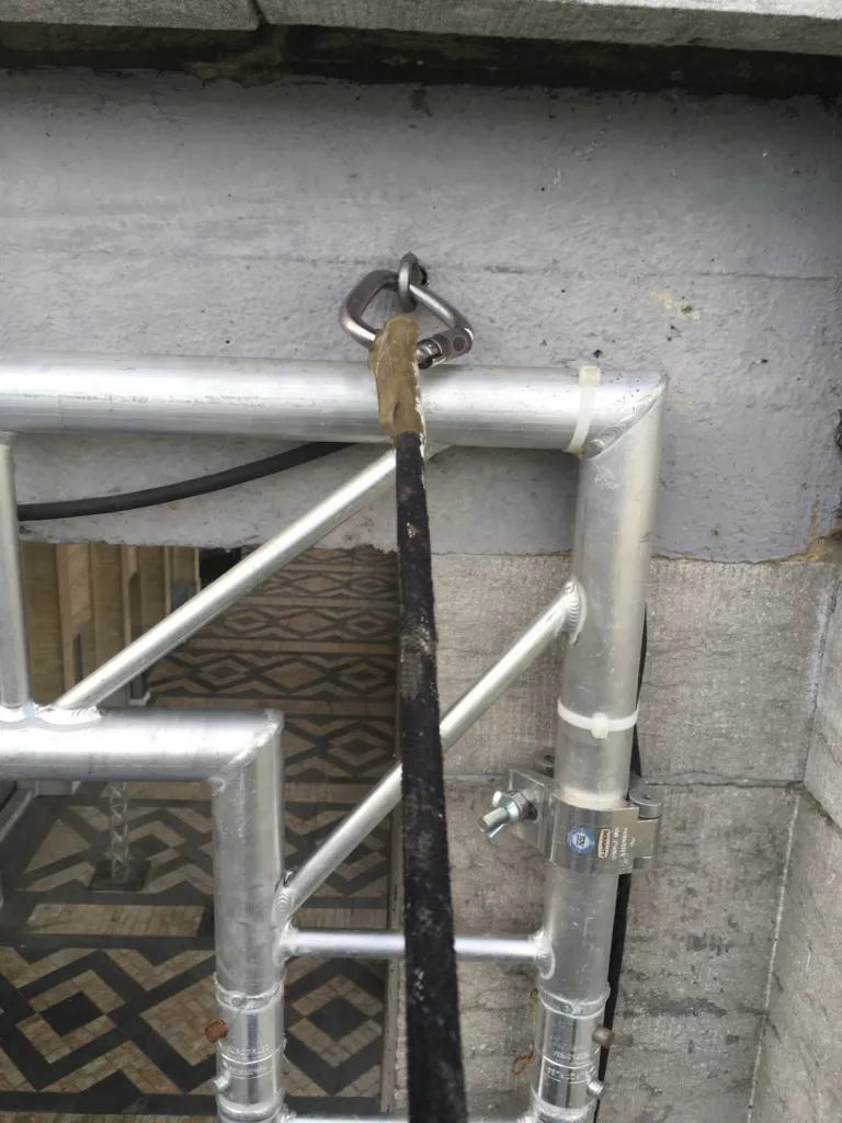 Détail d'une fixation du cadre métallique sur la façade en pierre