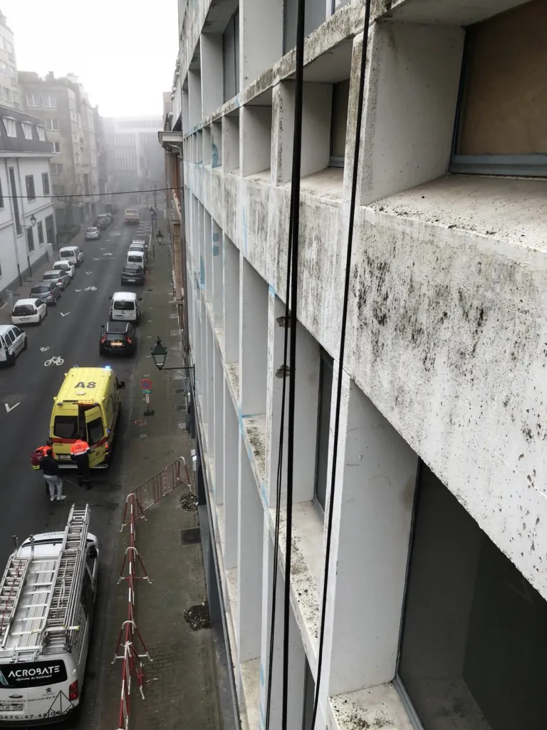 Le cordiste en hauteur au-dessus de la rue et des immeubles voisins