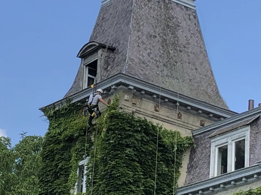Cordiste en intervention sous la corniche d'un château, au contact de la maçonnerie