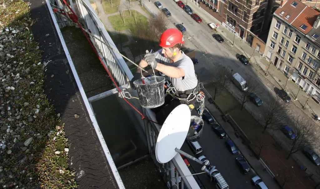 Vue plongeante depuis la toiture sur un cordiste au niveau des balcons