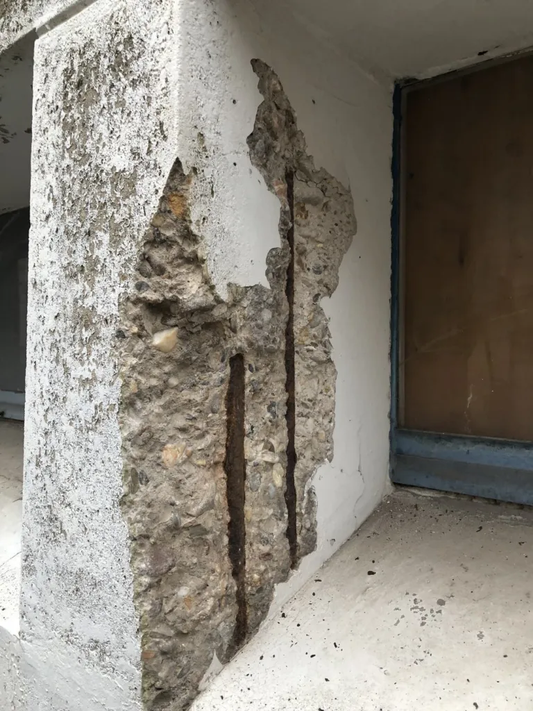 Béton éclaté sur un montant de façade, armature rouillée à nu : ce qui finit sur le trottoir si on ne le purge pas