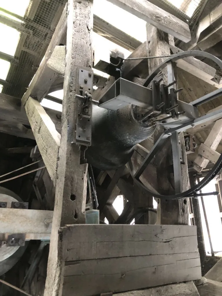 Une cloche suspendue dans la structure en bois du beffroi