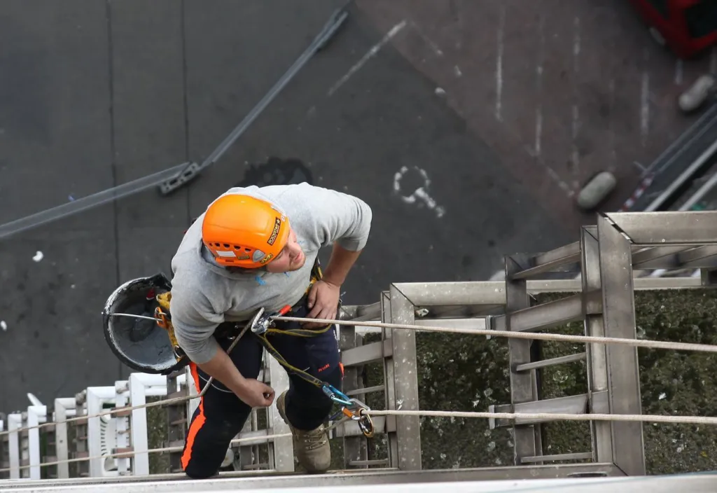 Un cordiste en descente le long des balcons, vu depuis la toiture