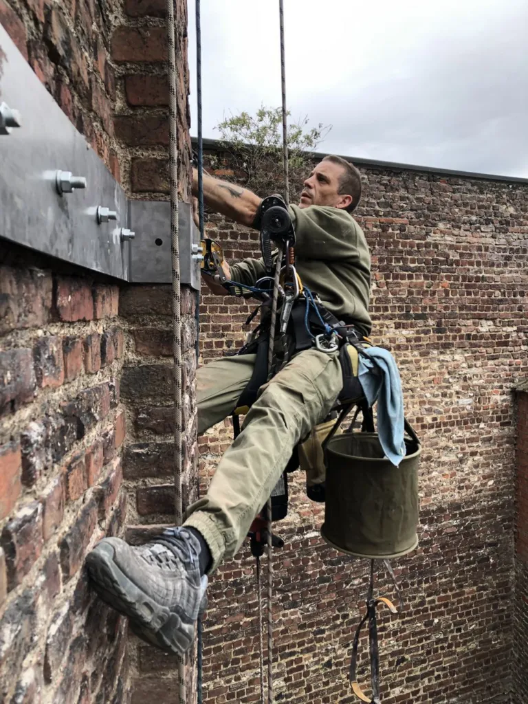 Le cordiste suspendu contre le mur en briques