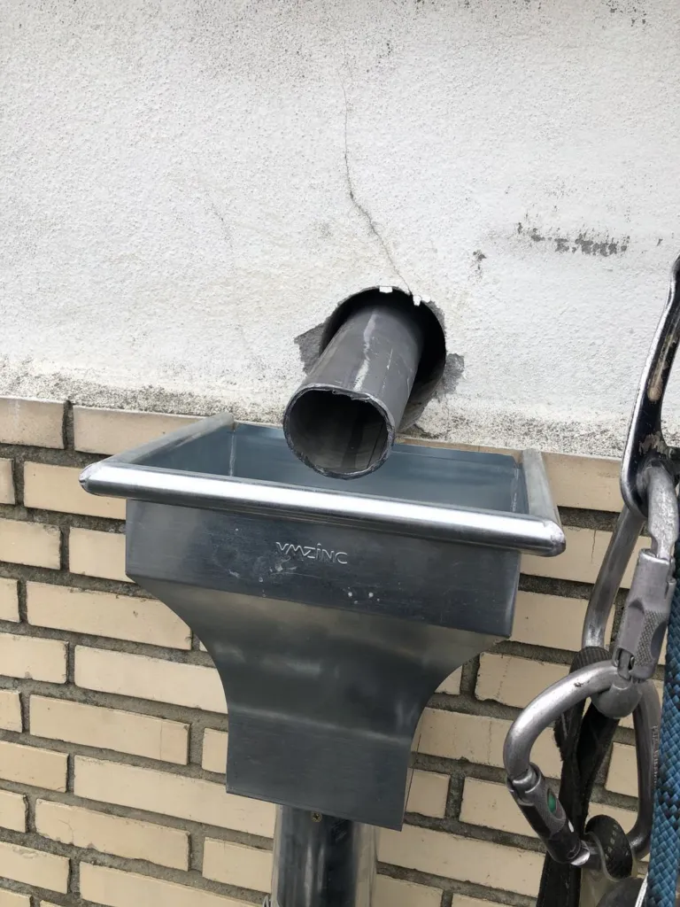 Boîte de collecte en zinc sous une sortie murale, sur une façade d'Etterbeek : le parcours de l'eau, de la sortie à la descente