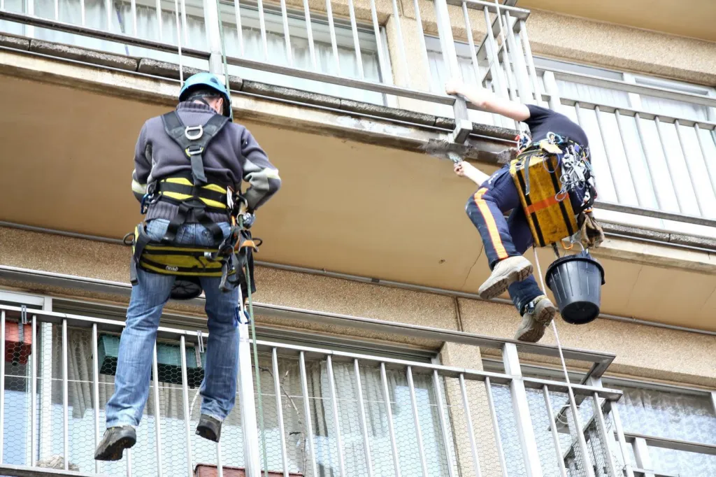 Un cordiste au travail au droit d'un balcon et de son garde-corps