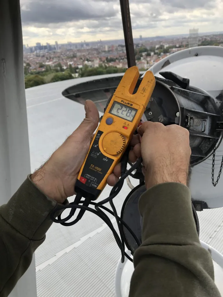 Mesure électrique sur un projecteur en tête de mât, la ville de Bruxelles en arrière-plan