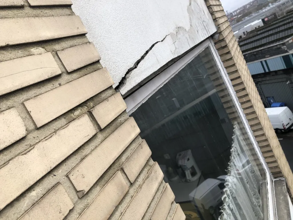 Enduit dégradé près d'une fenêtre en étage, relevé de près depuis la corde, à Etterbeek
