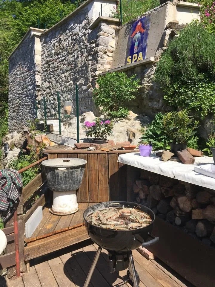 Le mur de soutènement restauré vu depuis la terrasse en contrebas, un barbecue au premier plan